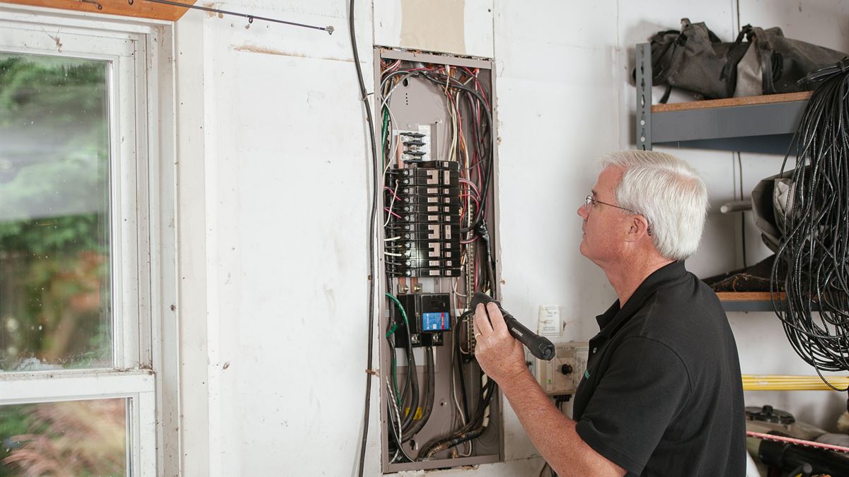 Dağıtım panosunda ölçüm yapan elektrik teknisyeni